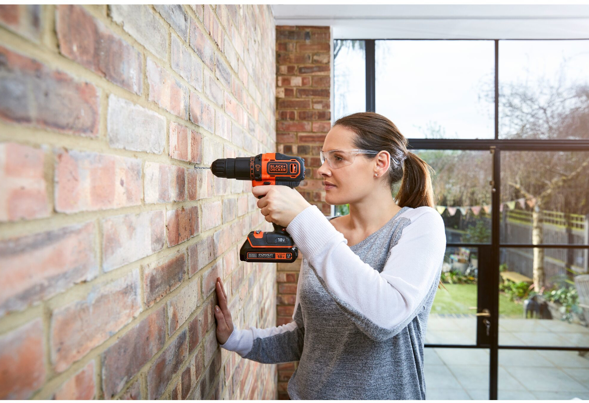Απεικονίζεται γυναίκα να χρησιμοποιεί το εργαλείο για διάτρηση σε τοίχο